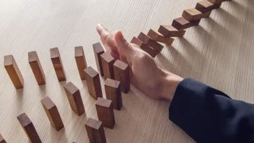Businesswoman hand stopping the domino wooden effect concept for business.