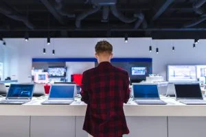Eine Person betrachtet Laptops in einem Elektronikgeschäft.