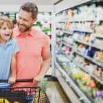 Father and son looking at product at grocery store. Dad with child in supermarket buying food