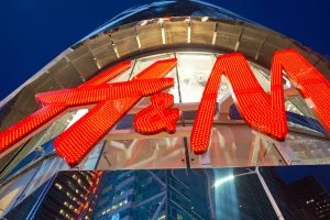 Red illuminated H&M sign on the facade of a building, seen from below.