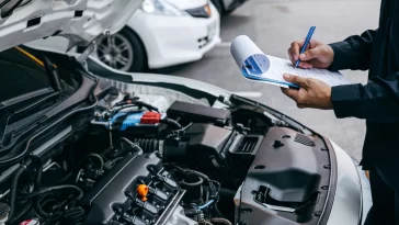 Mechanic check list to the clipboard insurance with inspecting car at garage workshop, Car auto services and maintenance check concept.