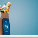 Grocery shopping app and grocery bag full of goods: online grocery shopping and home delivery concept, copy space
