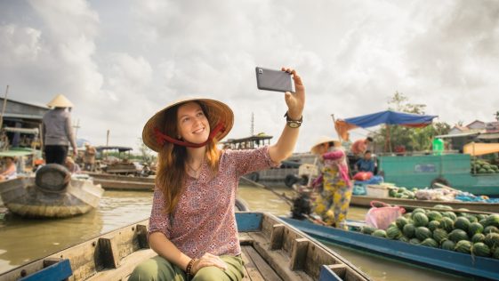 Woman tourist take selfie photo from the boat on Cai Rang floating market, Can Tho, Vietnam