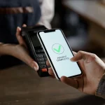 Pague por telefone celular em uma máquina de pagamento eletrônico ou leitor de cartão. Dinheiro eletrônico na carteira sem dinheiro do cliente. Macho com telefone celular e fêmea mãos com POS-terminal no close-up da loja. Comprando ordem de alimentos