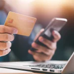 Close up Male hands holding credit card and smartphone, man paying online, credit card shopping, using banking service, entering information, shopping, ordering in internet store, doing secure payment