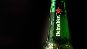 Garrafa de cerveja Heineken verde com gotas de condensação, em fundo escuro, destacando o logótipo da marca