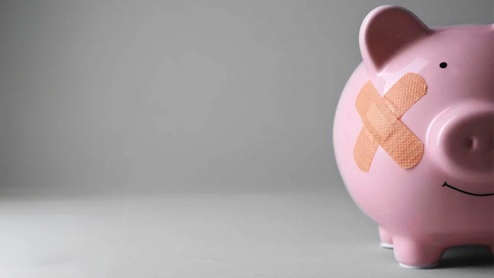 Mealheiro em forma de porco com penso adesivo, simbolizando dificuldades financeiras, insolvência e necessidade de recuperação económica