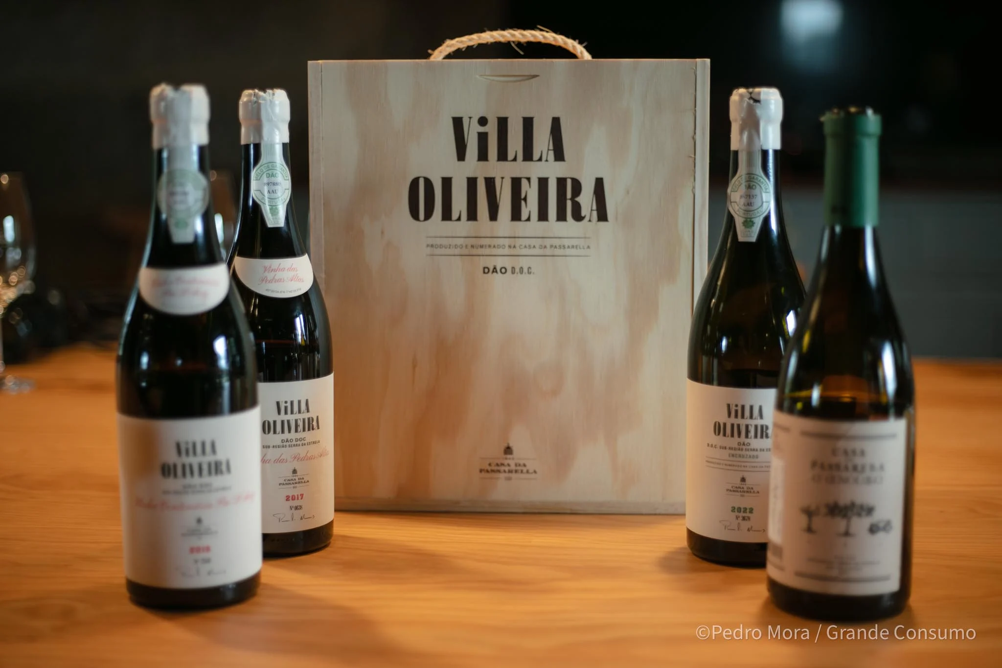 Garrafas de vinho Villa Oliveira Dão DOC junto a uma caixa de madeira da Casa da Passarella