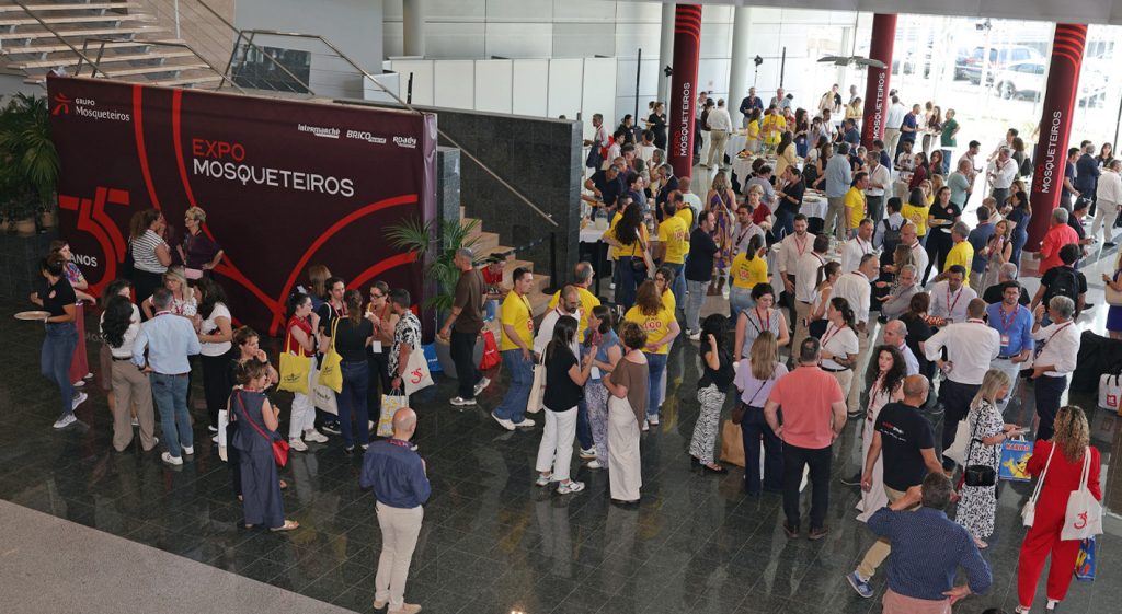 Participantes reunidos na Expo Mosqueteiros, num átrio com stands e faixas do evento