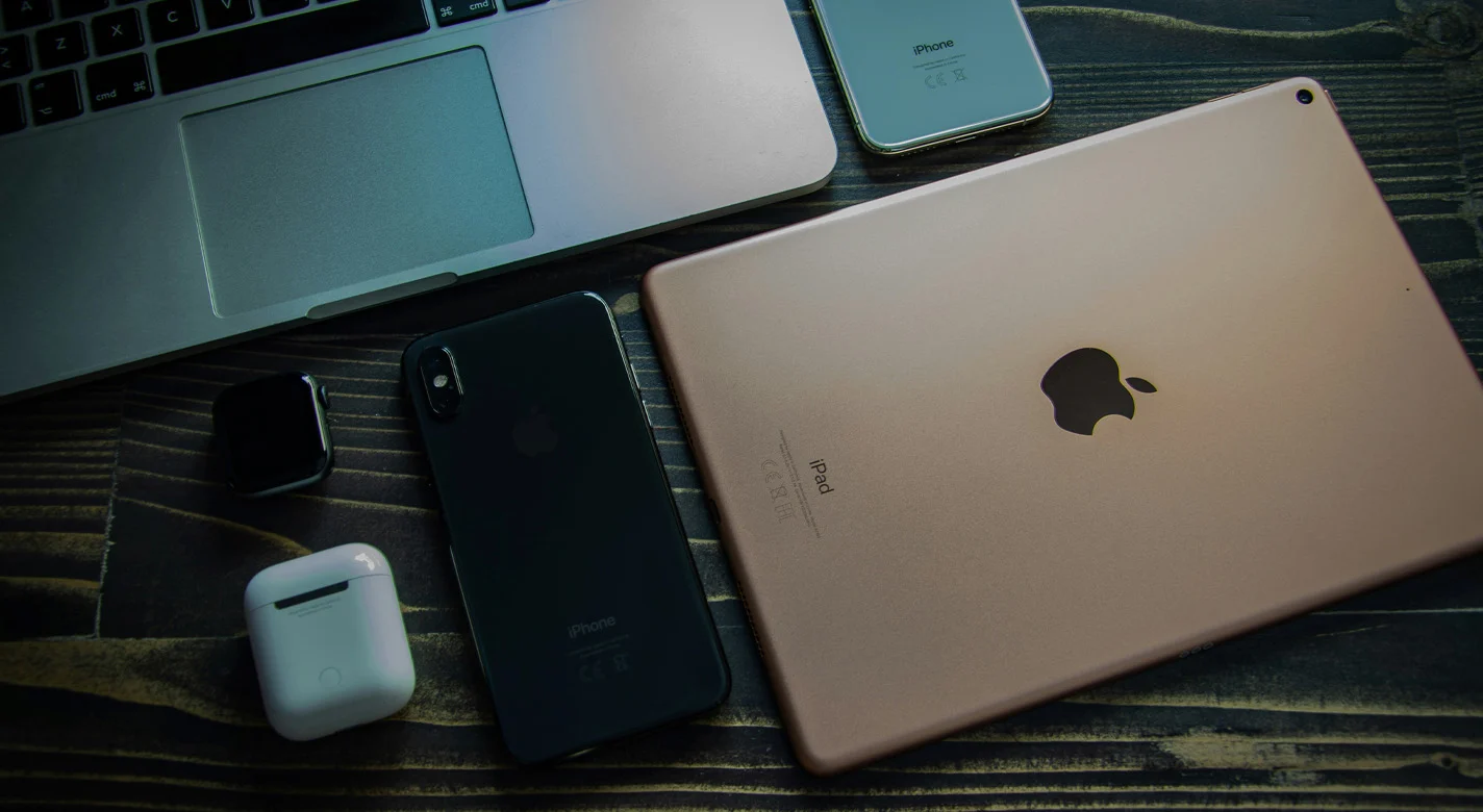 桌上的苹果设备：MacBook、iPad、iPhone、Apple Watch 和 AirPods。