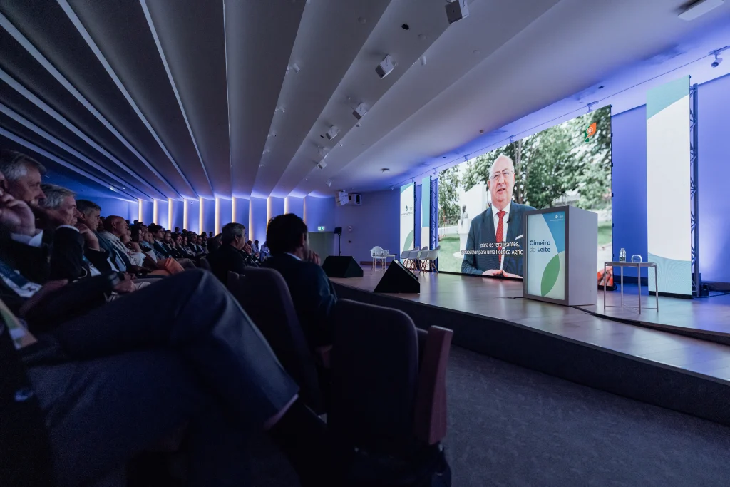 Auditório com público a assistir a uma apresentação da Cimeira do Leite da Lactogal numa grande tela