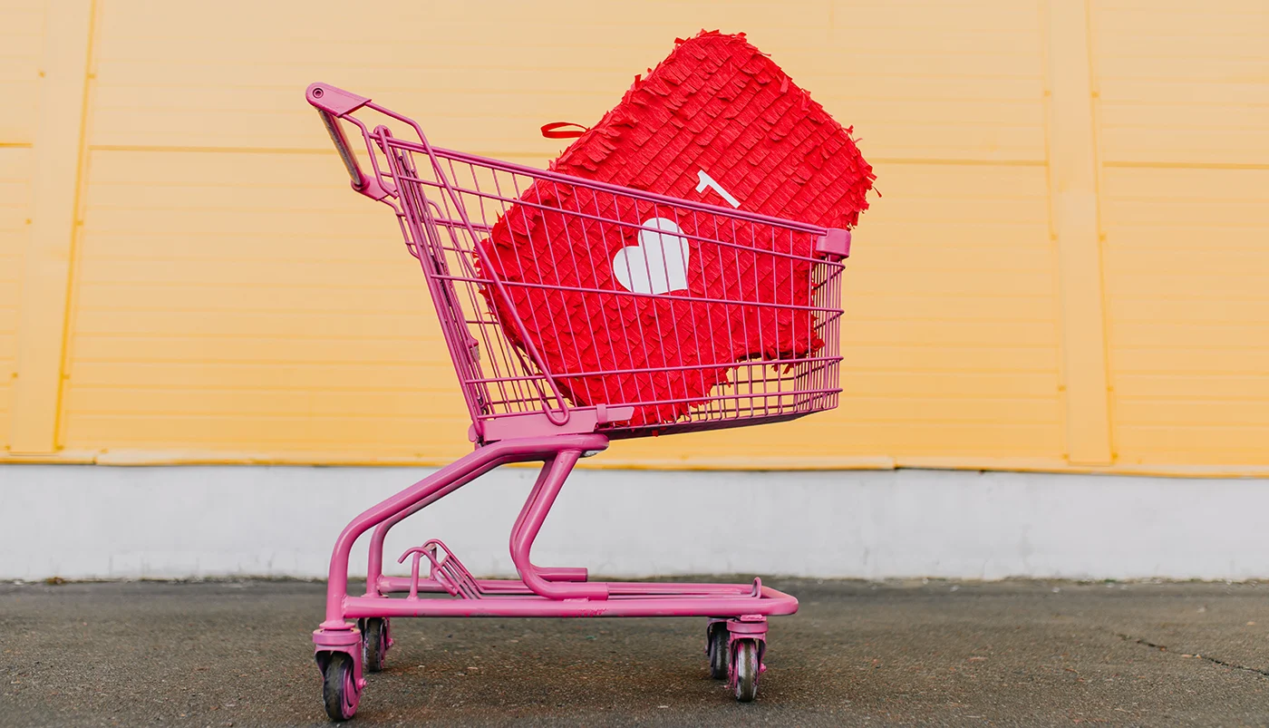 Carrinho de compras rosa com uma pinhata vermelha em forma de casa e um coração branco