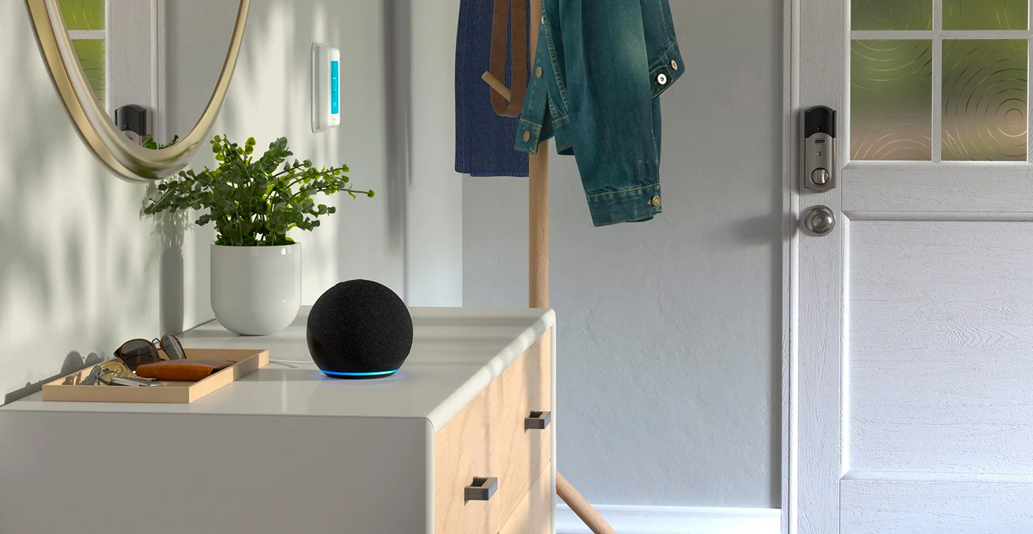 Coluna inteligente preta com luz azul sobre um aparador junto à entrada de uma casa