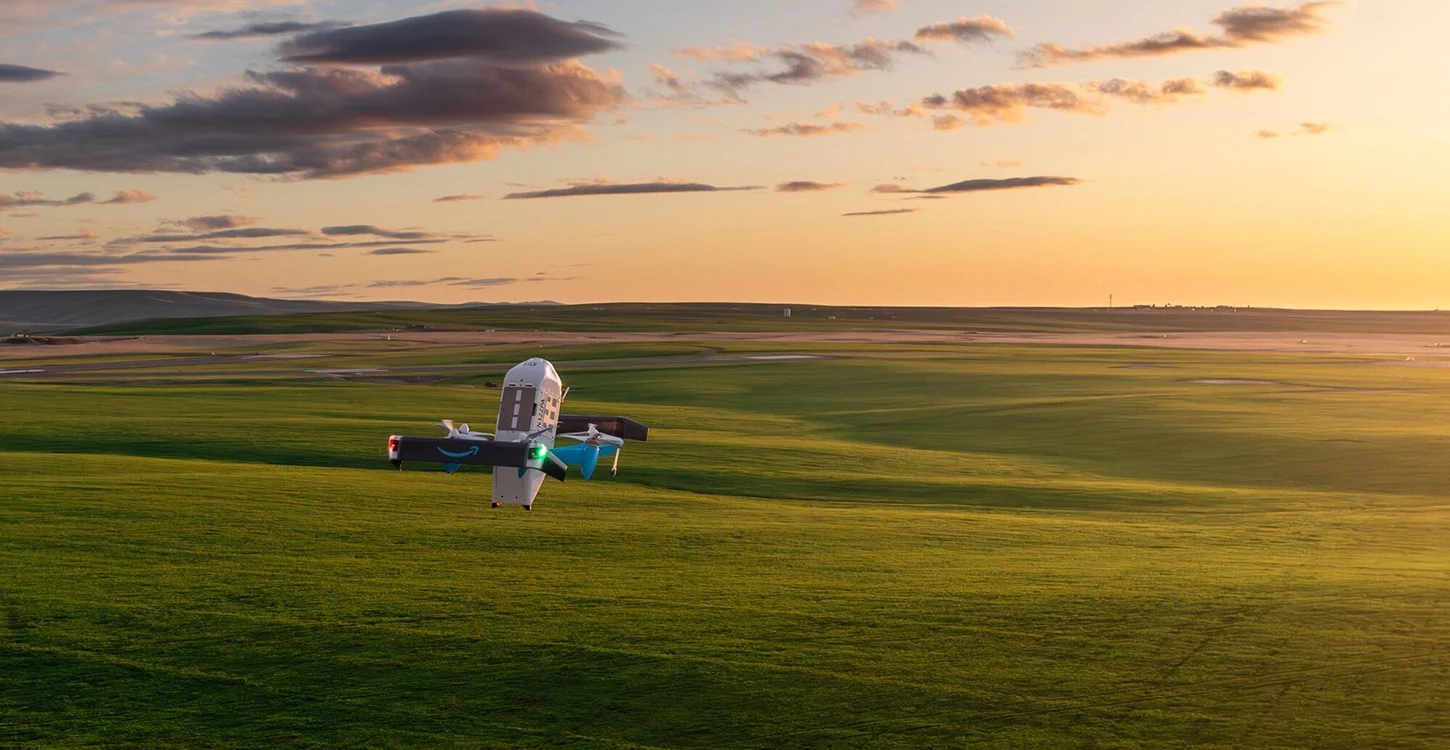 Drone de entregas da Amazon a voar sobre um campo verde ao pôr do sol