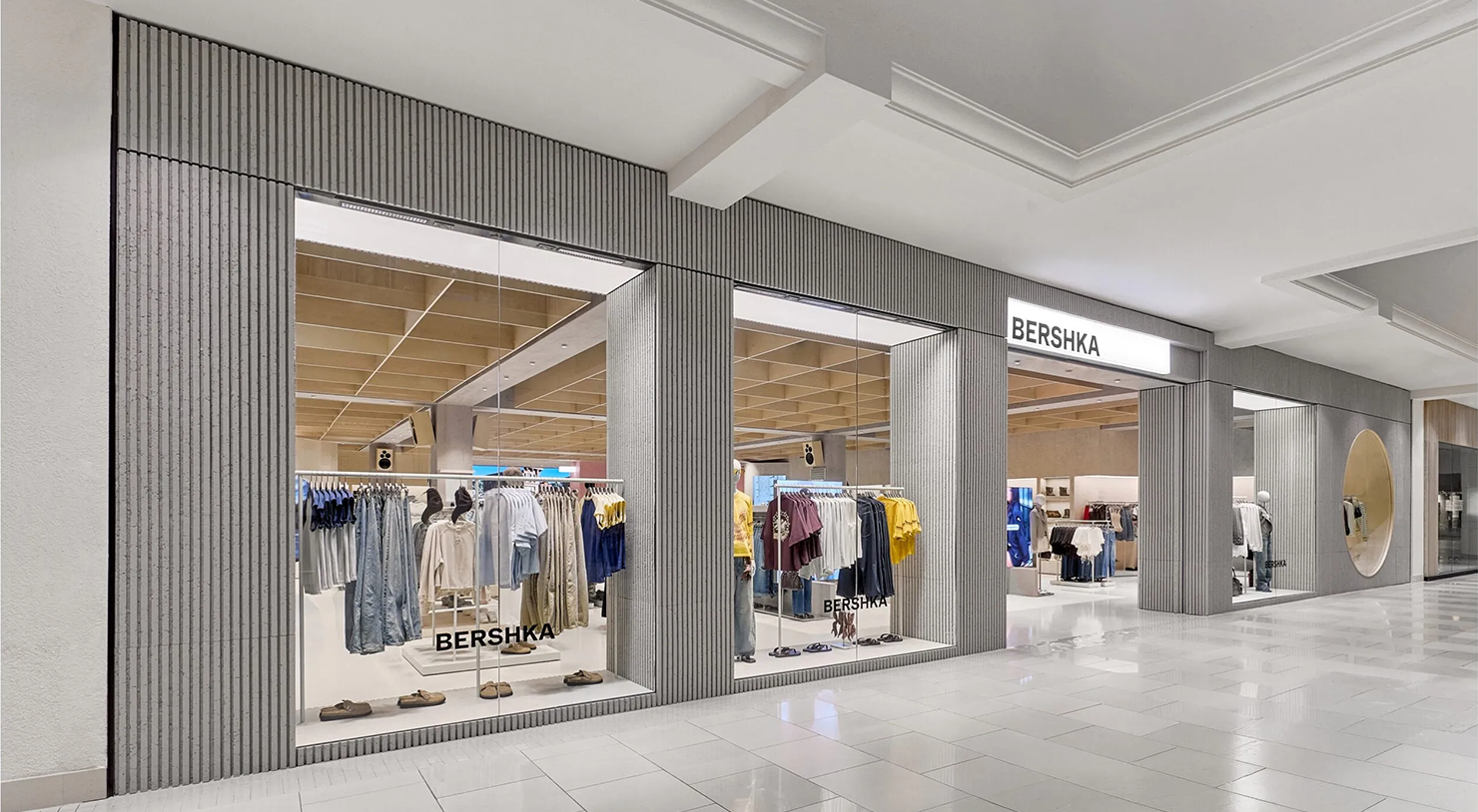 Montra da loja Bershka num centro comercial, com roupa exposta no interior