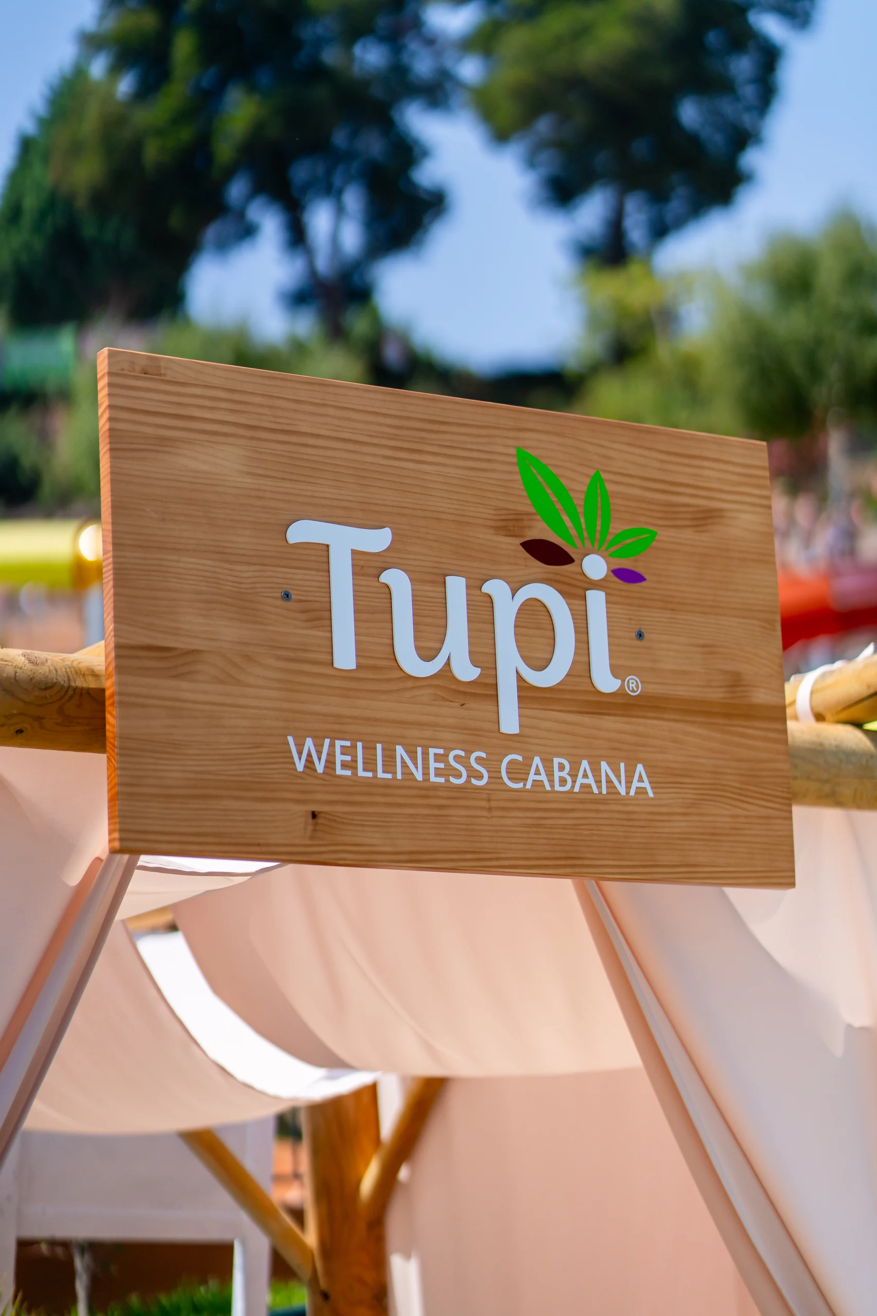 Placa de madeira com o logótipo Tupi e o texto “WELLNESS CABANA”