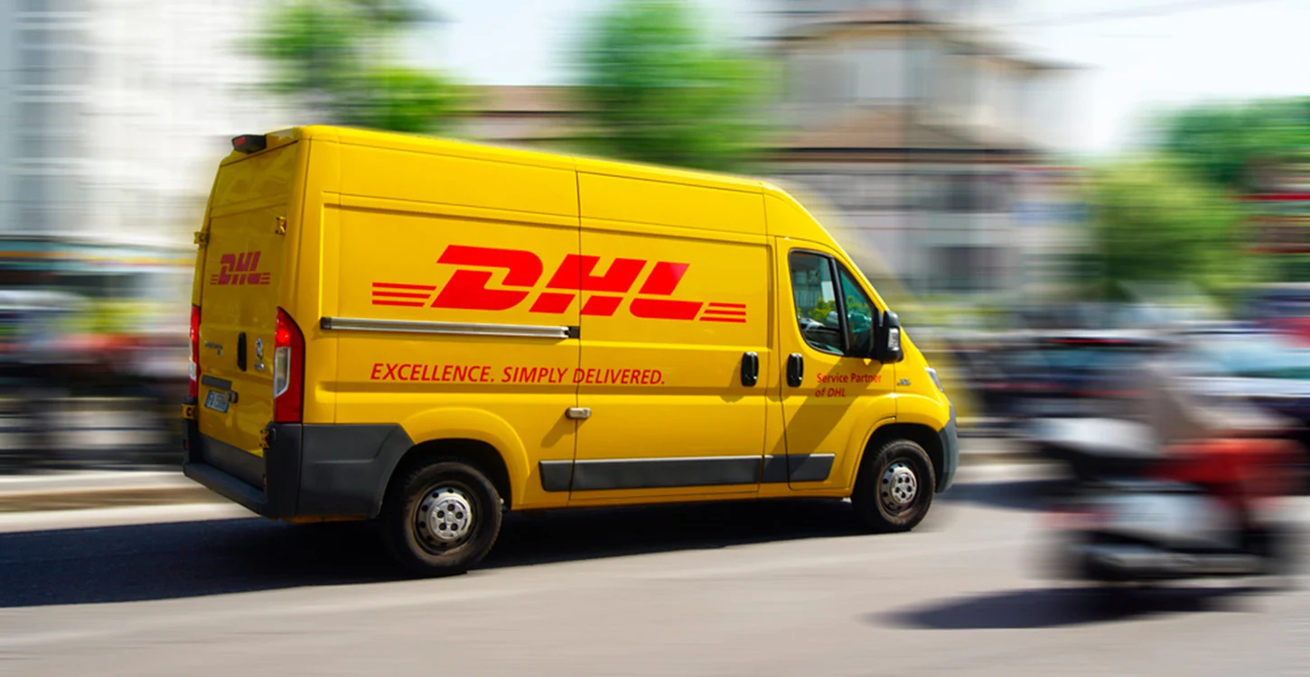 Carrinha de entregas da DHL em movimento numa rua urbana