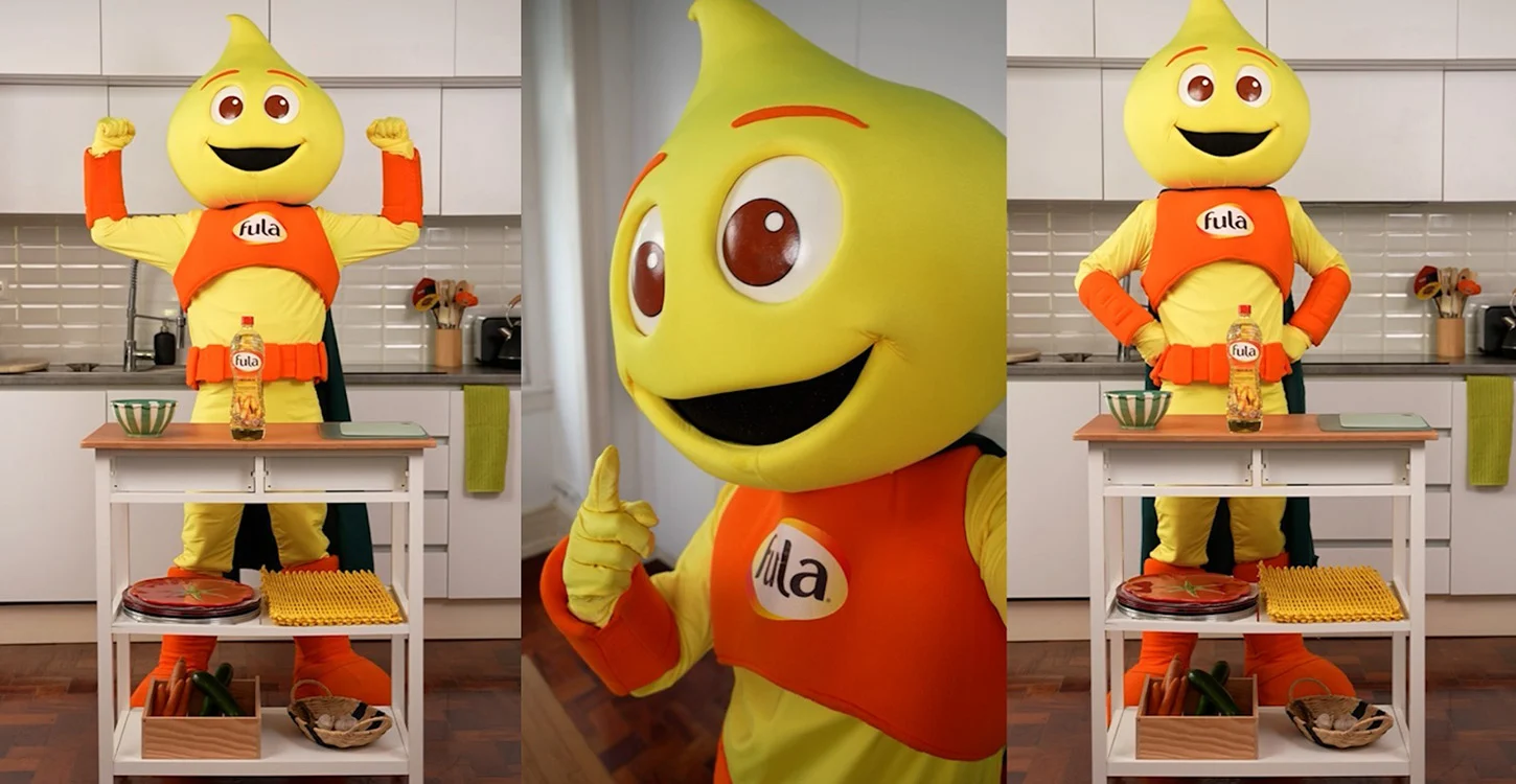 Mascote da Fula numa cozinha, ao lado de uma mesa com uma garrafa de óleo Fula e alimentos