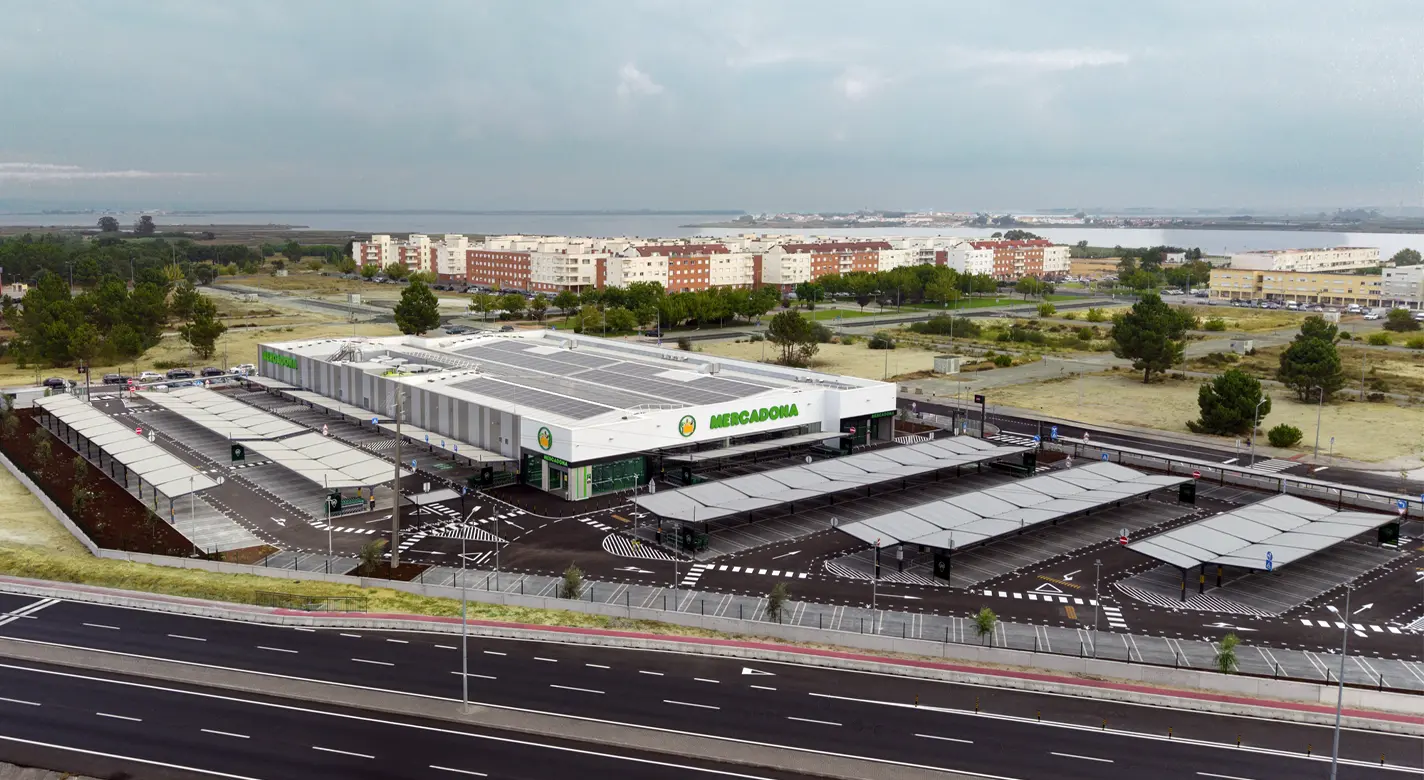 Vista aérea de um supermercado Mercadona com parque de estacionamento, junto a uma zona costeira