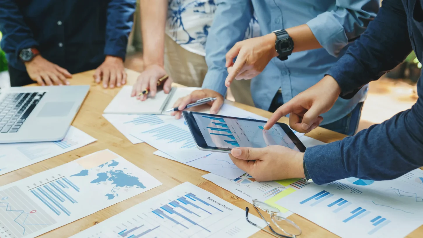 Equipa a analisar gráficos e relatórios num tablet e em papéis sobre a mesa