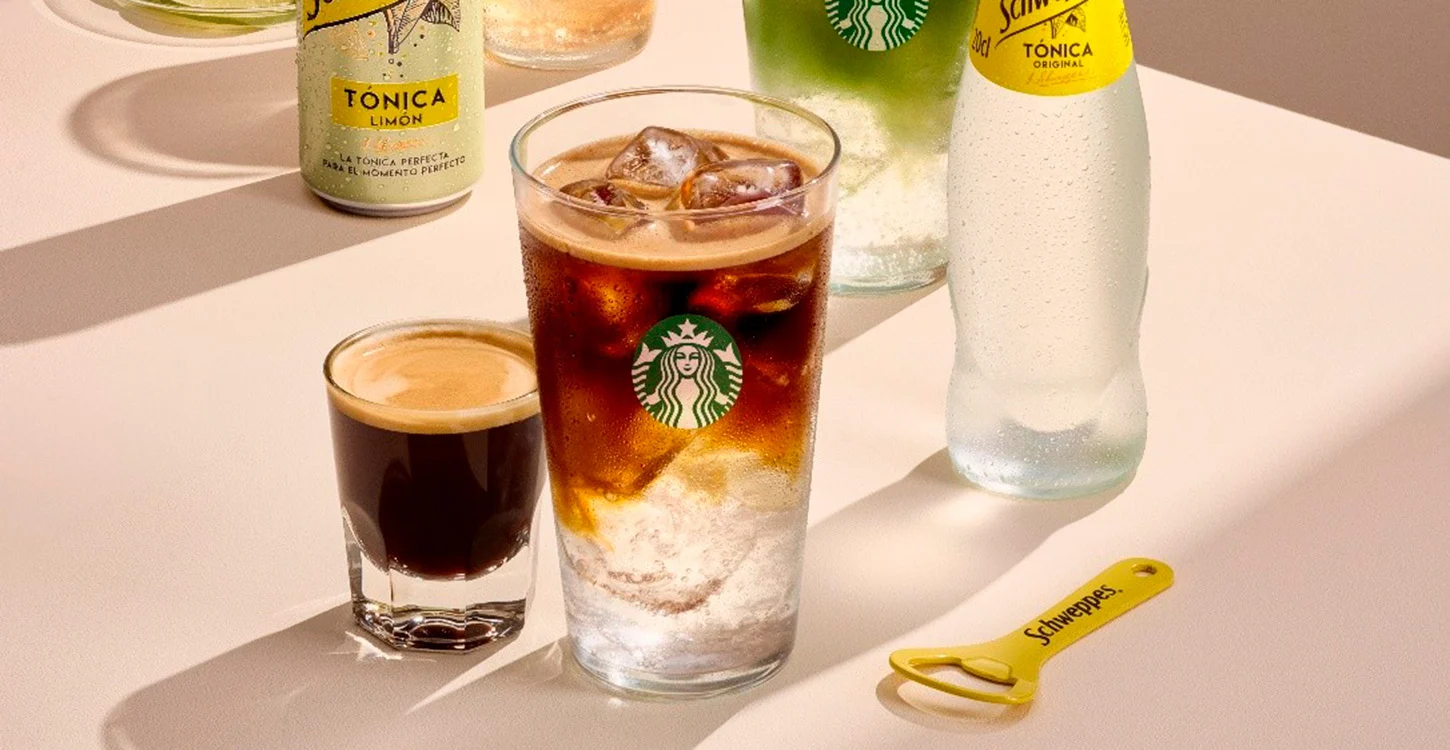 Copo de café gelado com gelo, acompanhado por um expresso, garrafas de água tónica e um abre-garrafas