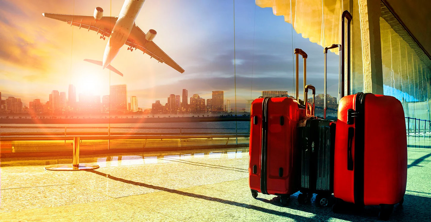 Malas de viagem vermelhas num aeroporto, com um avião a descolar ao fundo