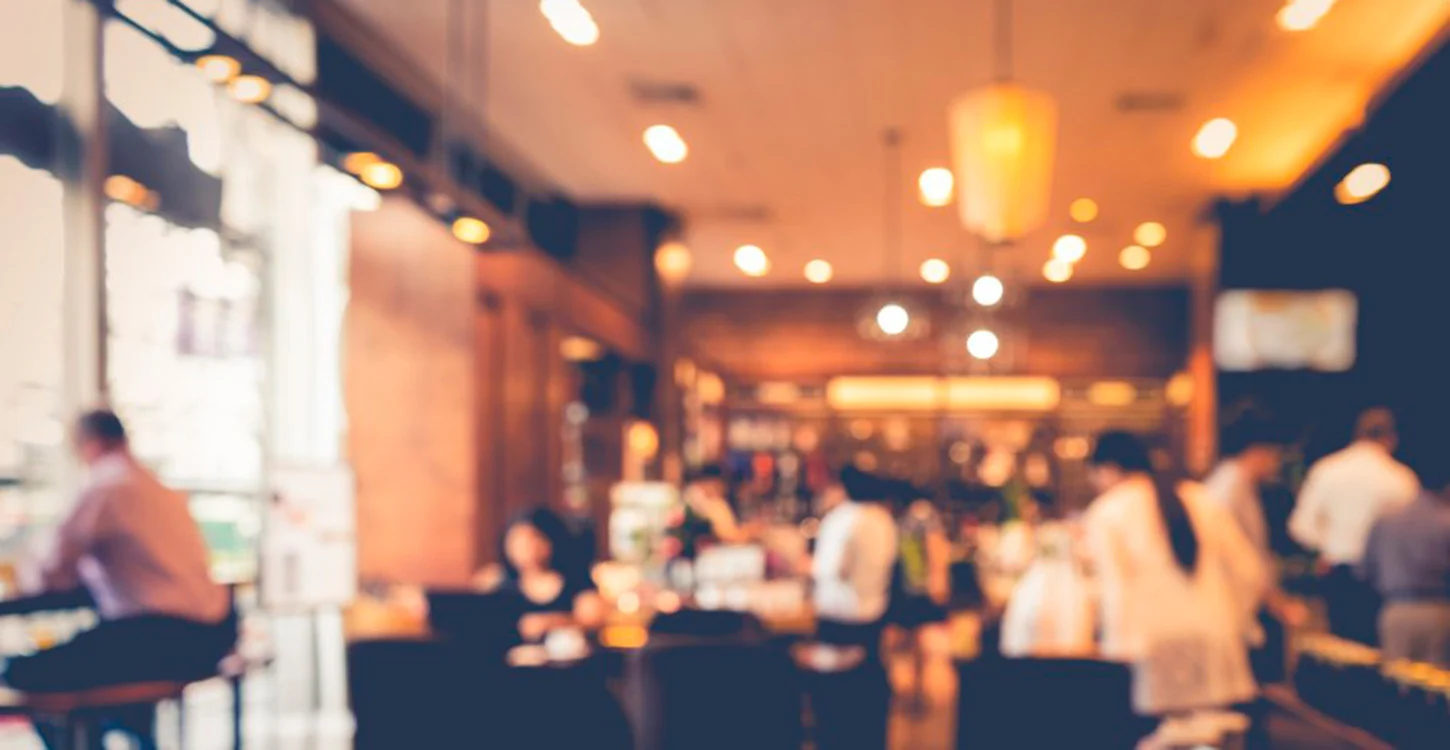 Interior acolhedor de um restaurante movimentado, com várias pessoas a jantar
