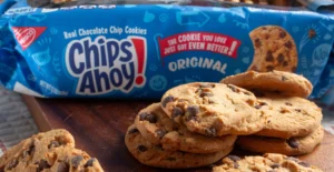 Embalagem azul de bolachas Chips Ahoy! Original junto a uma pilha de bolachas com pepitas de chocolate