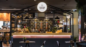 Balcão de uma cafetaria Delta Coffee House, com máquinas de café, recipientes de grãos e mesas