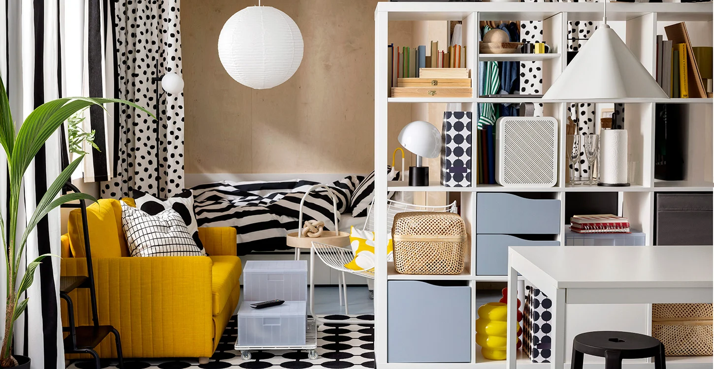 Interior de uma divisão colorida, com poltrão amarelo, cama, estante branca e decoração a preto e branco