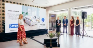 Apresentação da JYSK com uma oradora e quatro participantes, perante um ecrã que celebra 10 anos em Portugal
