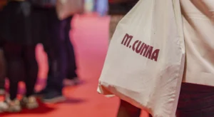 Saco de pano branco com a inscrição «M. CUNHA», num ambiente iluminado a vermelho
