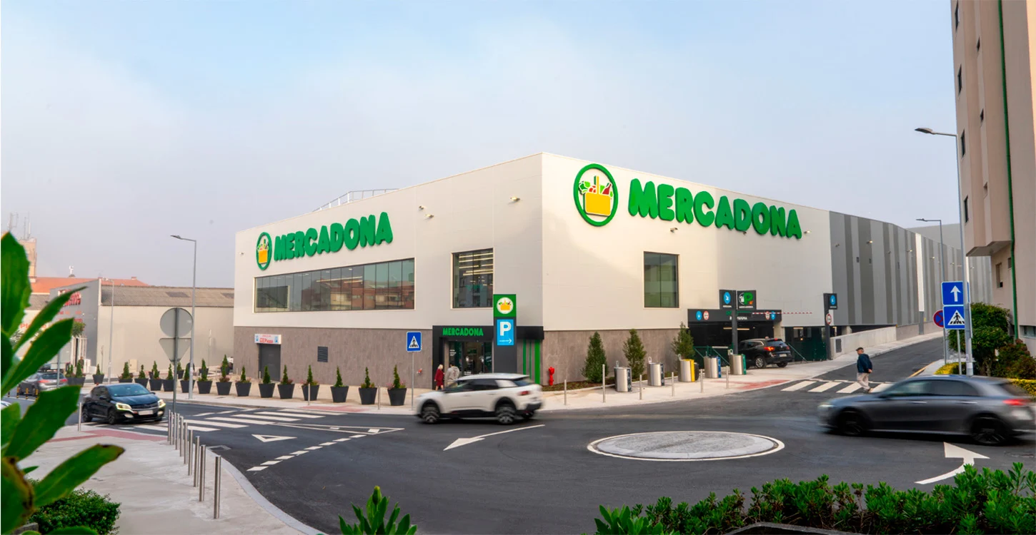 Edifício de um supermercado Mercadona, junto a uma rua com carros, passadeiras e estacionamento