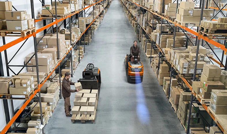 Operadores preparam encomendas num armazém com equipamentos Toyota Optio L e corredores repletos de estantes
