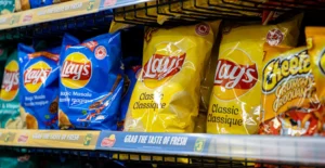 Prateleira de supermercado com pacotes de batatas fritas Lay’s e Cheetos
