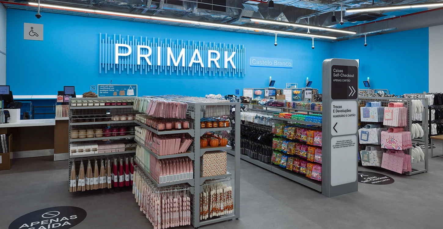 Interior da loja Primark em Castelo Branco, com expositores de produtos e caixas de self-checkout