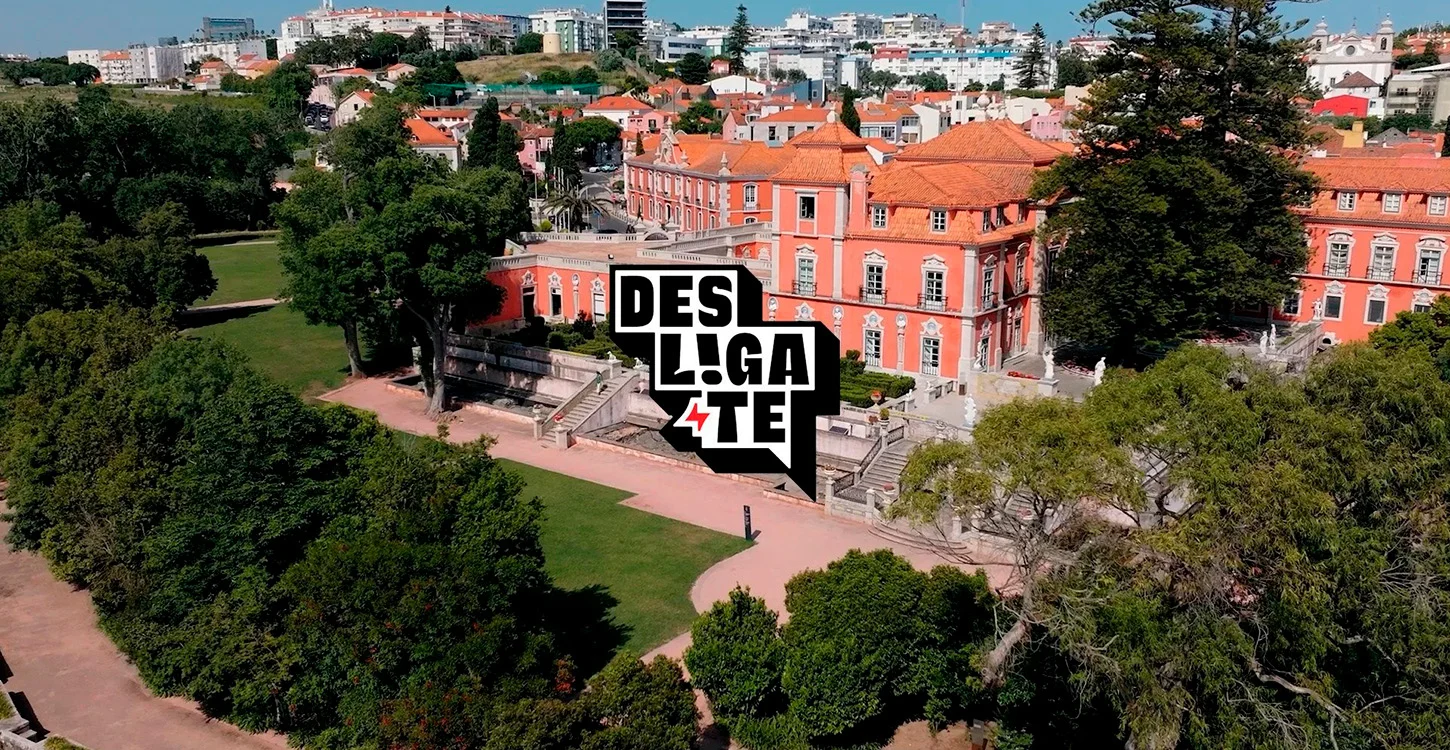 Vista aérea de um palácio cor-de-rosa rodeado por jardins, com o logótipo «Desliga-te» em primeiro plano