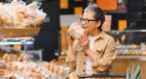 Mulher numa padaria de supermercado a escolher um pão embalado