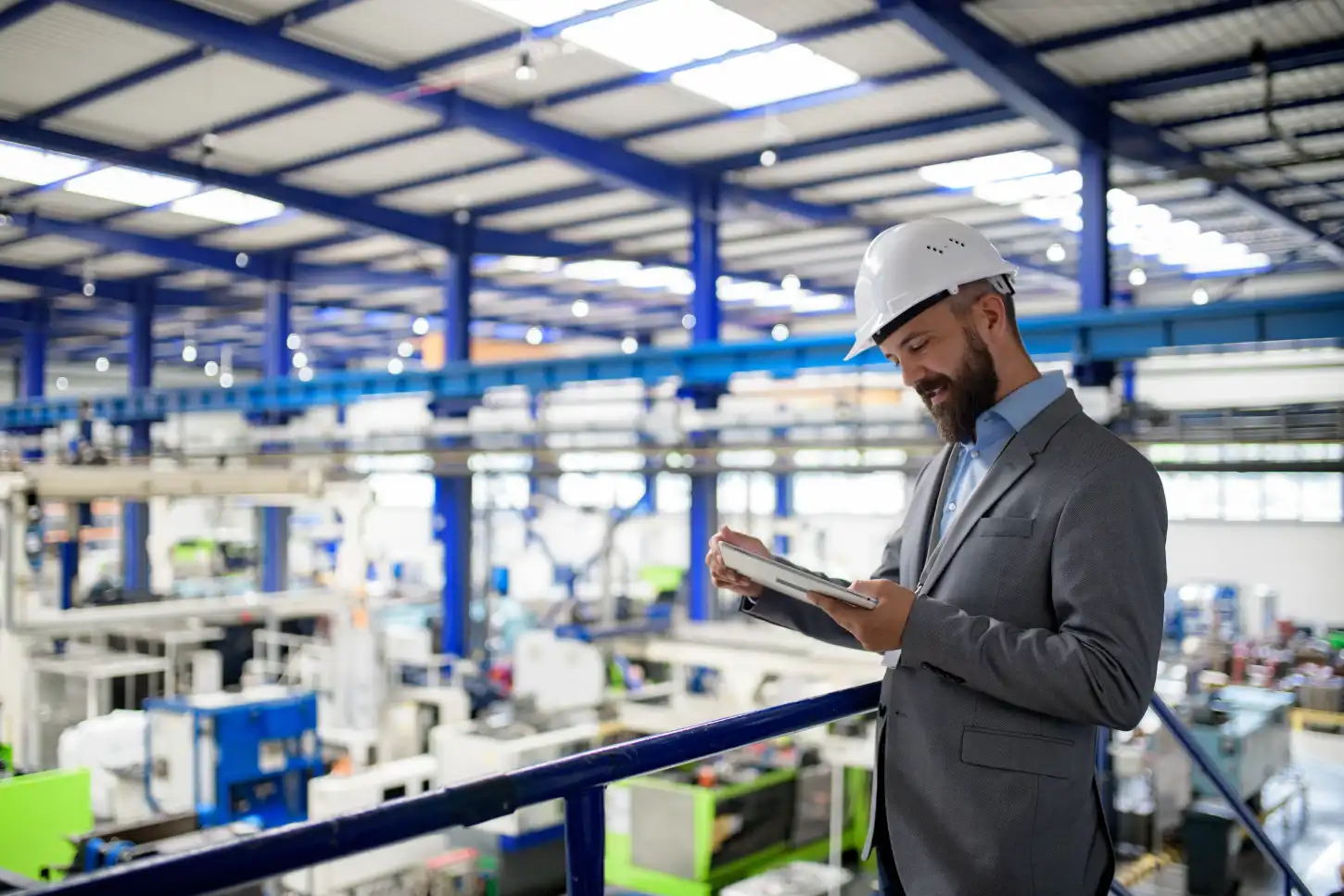 Um engenheiro de capacete consulta um tablet numa fábrica industrial