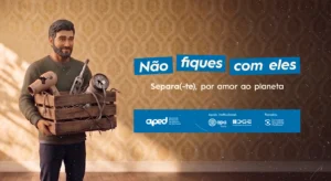 Homem segura uma caixa com resíduos electrónicos; cartaz: «Não fiques com eles. Separa(-te), por amor ao planeta»