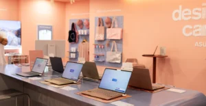 Exposição de computadores portáteis numa loja, com acessórios e vestuário expostos ao fundo