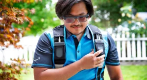 Estafeta com óculos e uniforme azul a comunicar através de um rádio portátil
