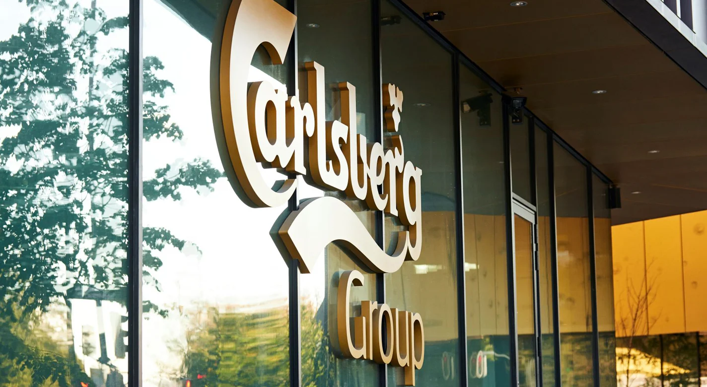 Logótipo “Carlsberg Group” na fachada envidraçada de um edifício