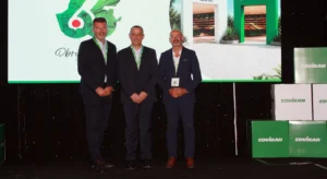 Três homens posam num palco diante de um ecrã e elementos com o logótipo Covirán