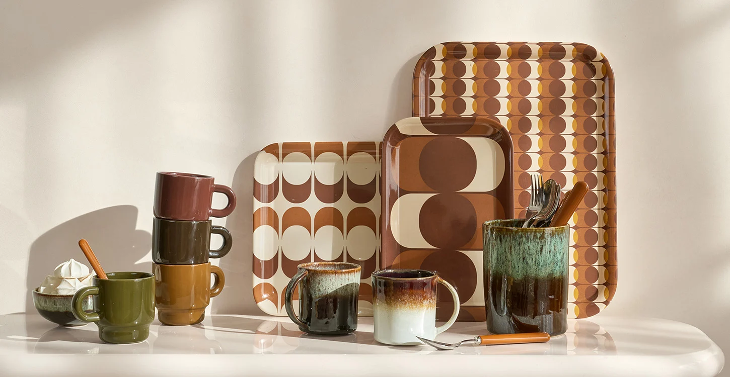 Composição de canecas, chávenas, jarro e tabuleiros com padrões geométricos em tons castanhos e creme