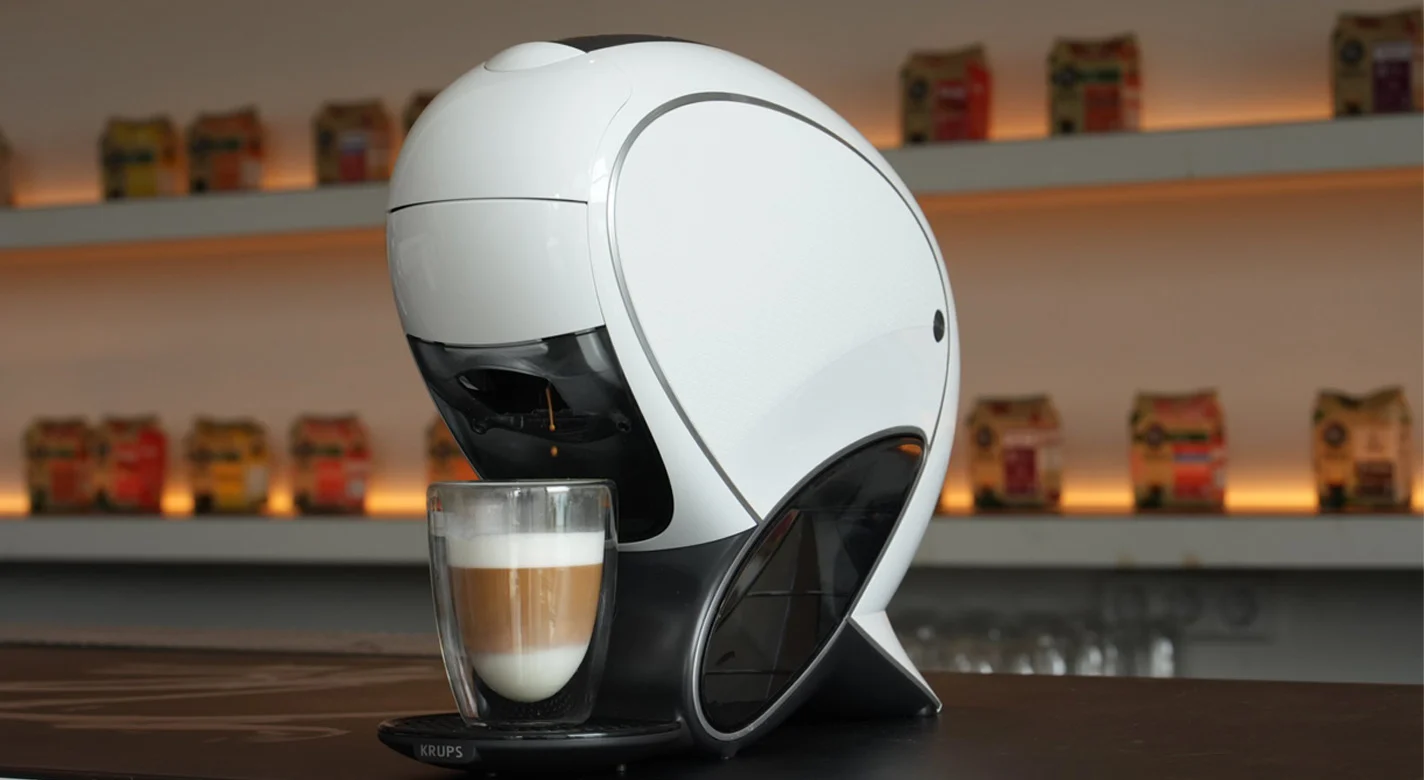 Máquina de café branca a preparar um latte num copo de vidro