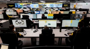Centro de operações de segurança com vários profissionais a monitorizar dezenas de ecrãs