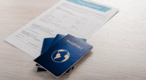 Closeup de formulário de reivindicação de seguro de viagem parcialmente coberto por três passaportes azuis na mesa de madeira clara, o topo do formulário mostra a leitura do cabeçalho Seguro de viagem com campos impressos visíveis e caixas de seleção