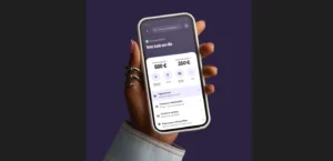 Mão segura um telemóvel com uma aplicação financeira que mostra 500 € na conta e 350 € de saldo disponível