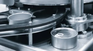 Máquina industrial de processamento de latas, com uma lata aberta e outra selada com argola